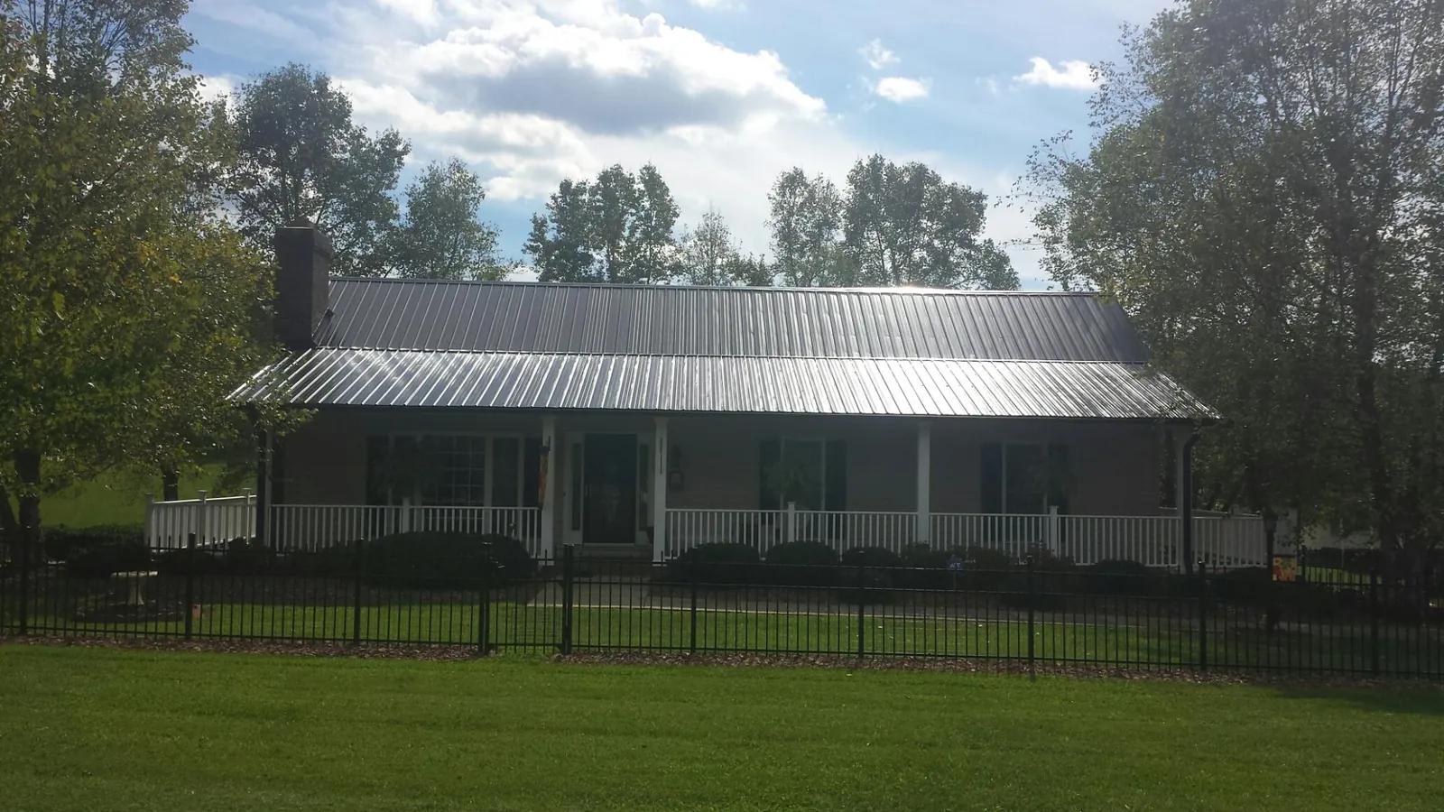 Gray metal roof on a brick ranch with a full width front porch — Gutter Guard Installation work by our crew in Farmville