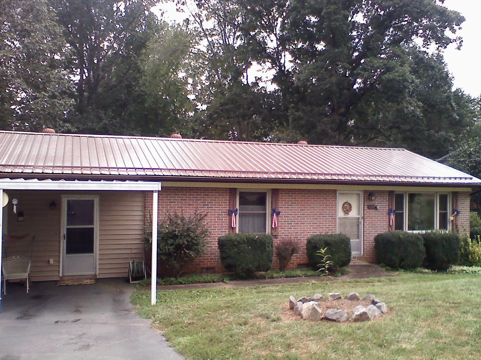Bronze metal roof and carport on a brick ranch home — Roof Repair work by our crew in Farmville
